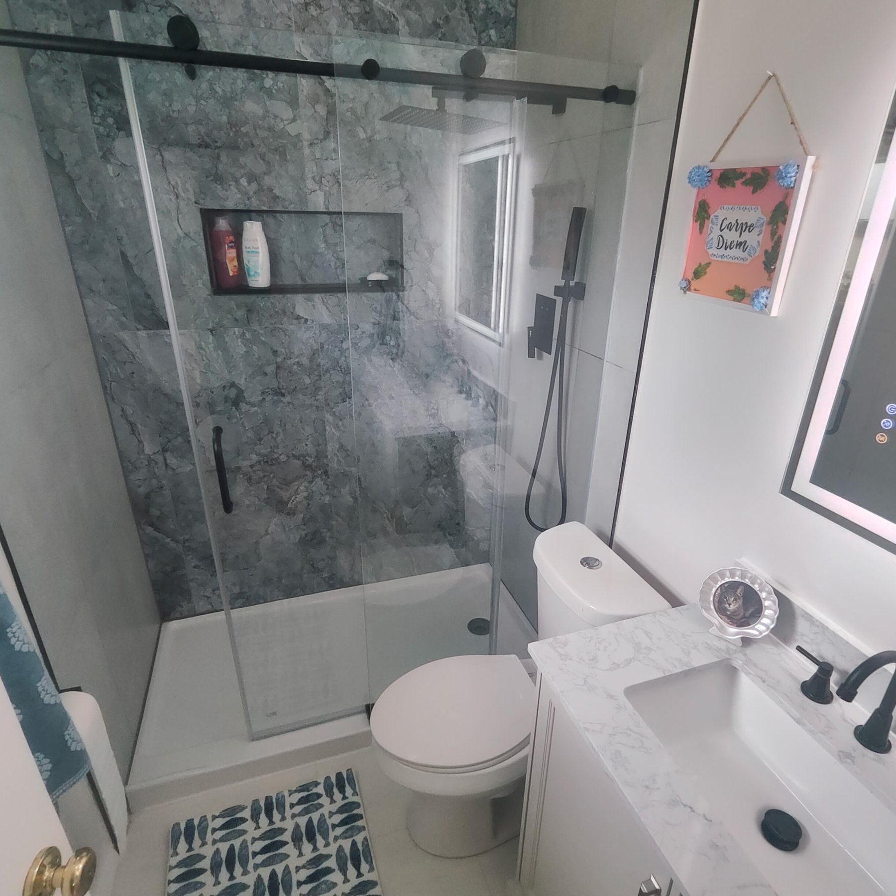 Finished glass shower with black fixtures and marble-look tile