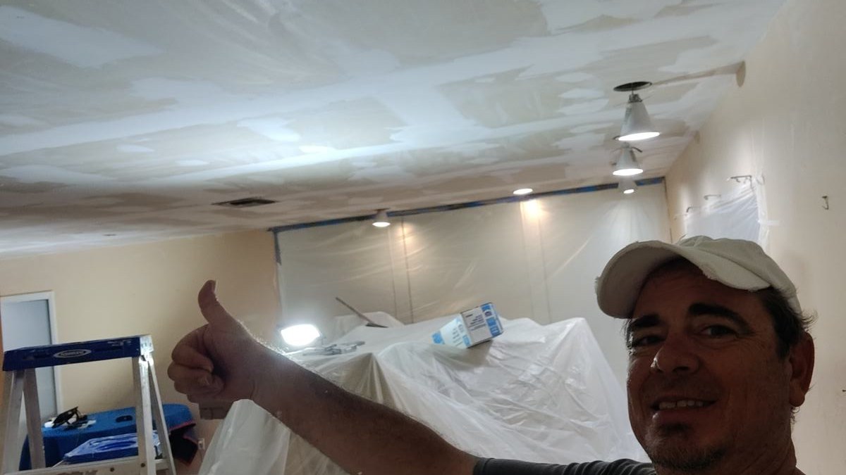John giving a thumbs-up during ceiling repair and finishing